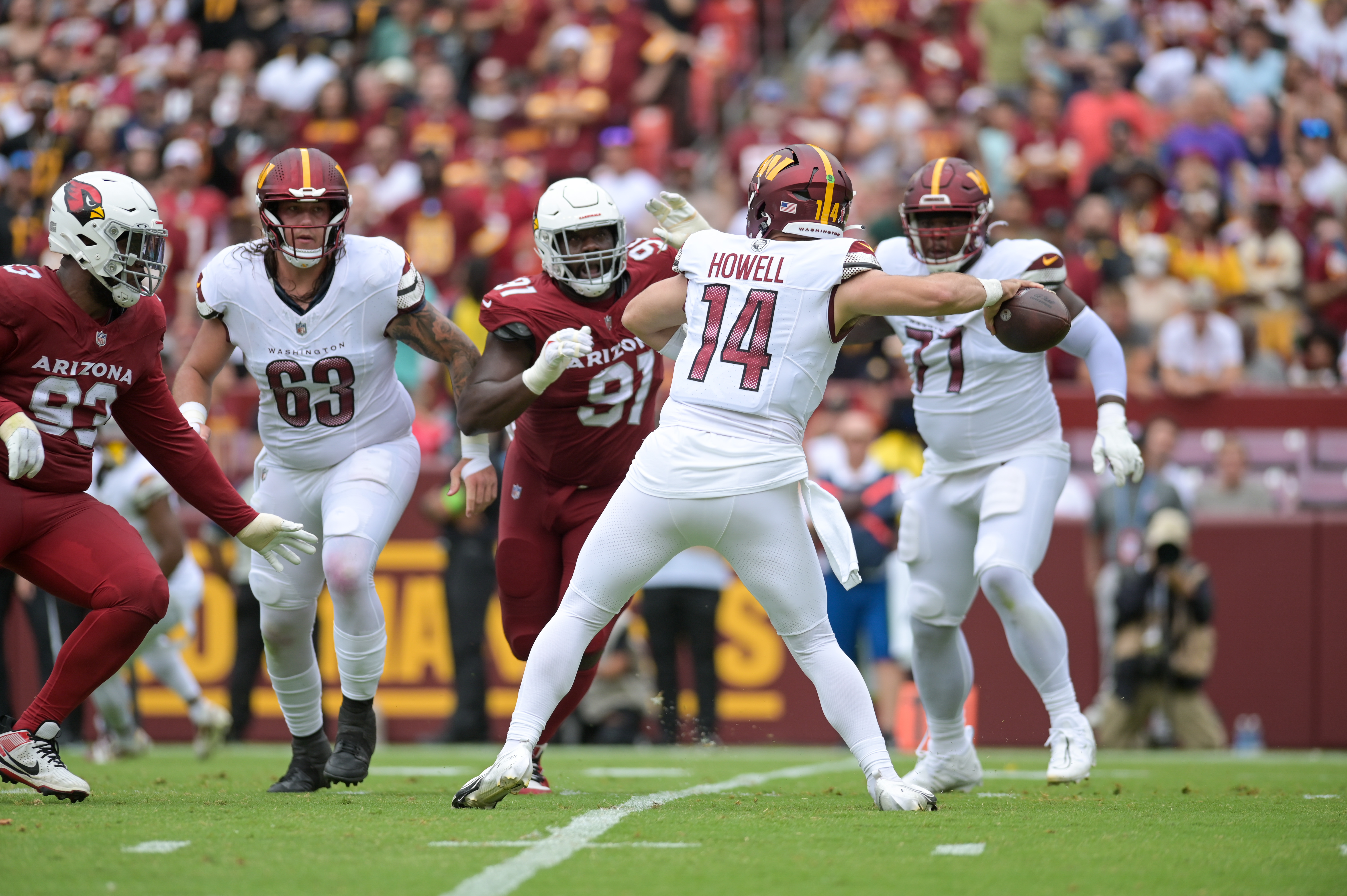 Sam Howell (14) winds up to throw while Nick Gates (63) watches the play.